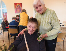 Bewohner*innen binden Palmbuschen aus Zweigen und Palmkätzchen an einem Arbeitstisch.