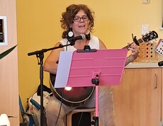 Eine Musikerin begleitet die Veranstaltung zum Tag der Demenz mit Gesang und Gitarrenspiel und lädt die Bewohner*innen zum gemeinsamen Mitsingen ein.