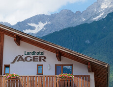 Frontansicht des Tiroler Gasthaus "Landhotel Jäger" vor alpiner Bergkulisse.