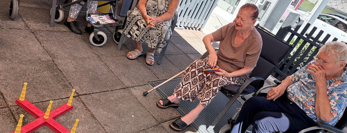 Bewohner*innen nehmen an einem Ringwurfspiel auf der Terrasse des Pflegewohnhauses teil.