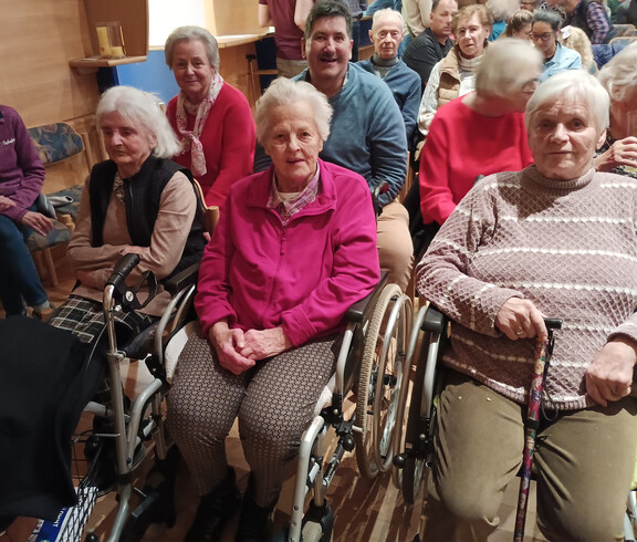 Bewohner*innen des Haus Michael sitzen im Kulturhaus Obervellach im Publikum des Theaterstücks und verfolgen die Aufführung.