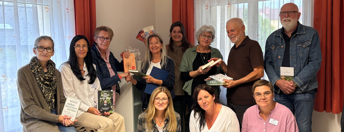 Eine Gruppe Erwachsener schaut in die Kamera und jeder hält ein Buch in der Hand