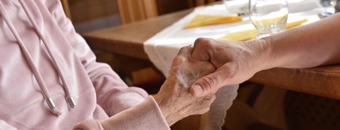 Eine Hand greift die Hand einer alten Frau