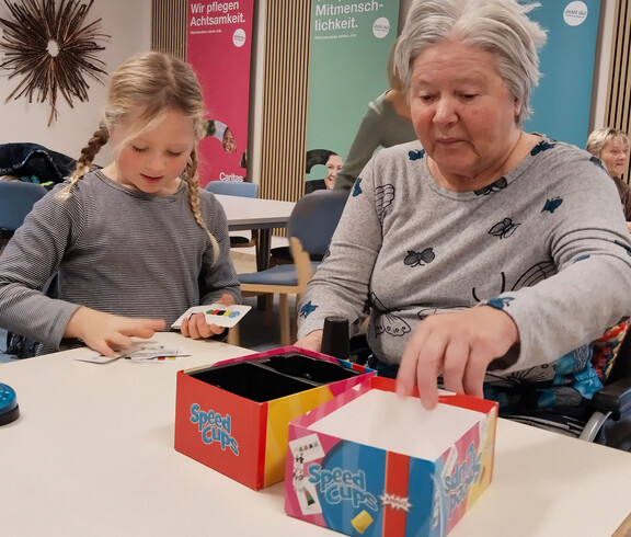 Kind und Senior*in spielen gemeinsam das Spiel „Speed Cups“