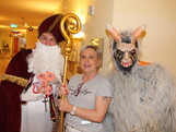 Nikolaus und Krampus posieren vor der Kamera, in der Mitte steht eine Pflegerin und hält den Stab des Nikolaus.