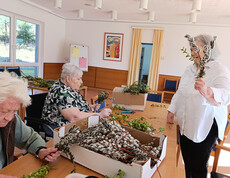 Fertige Palmbuschen liegen gesammelt in einem Korb auf einem Tisch im Pflegewohnhaus.