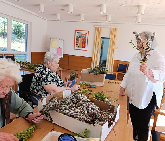 Fertige Palmbuschen liegen gesammelt in einem Korb auf einem Tisch im Pflegewohnhaus.