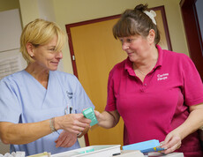 Zwei Pflegekräfte bereiten Medikamente an einem Wagen vor