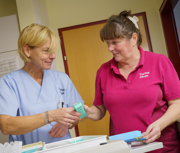 Zwei Pflegekräfte bereiten Medikamente an einem Wagen vor