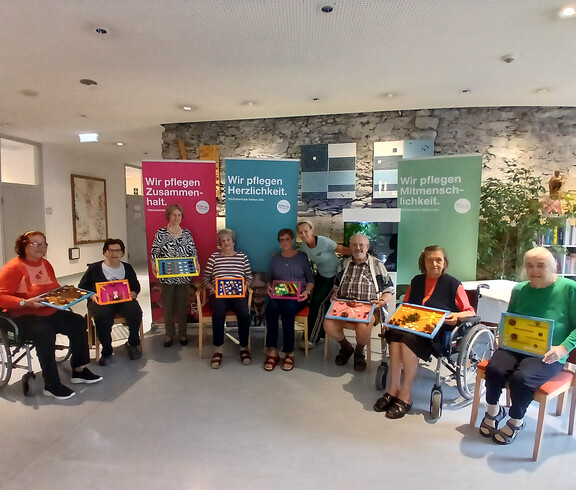 Bewohner*innen präsentieren selbst gestaltete Naturkunstwerke zum Weltalzheimertag in einem Caritas-Pflegewohnhaus.