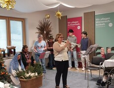 Mitarbeitende und Zivildienstleistende musizieren bei Weihnachtsfeier im festlich geschmückten Raum