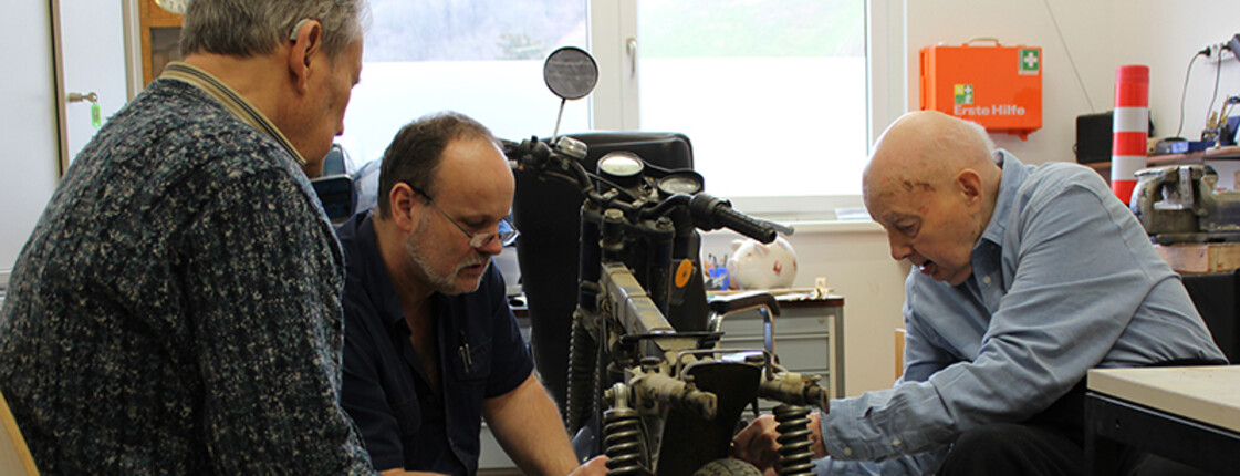 Tagesgast Otmar Schober, Haustechniker Georg Ponzer und Bewohner Fritz Brandl werkeln am Motorrad in der Werkstatt