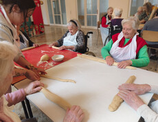 Bewohner*innen formen gemeinsam Reindling-Teig an einem Tisch im Pflegewohnhaus.