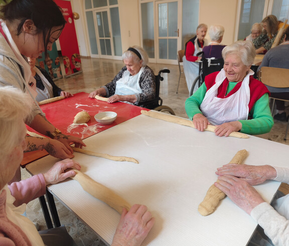 Bewohner*innen formen gemeinsam Reindling-Teig an einem Tisch im Pflegewohnhaus.