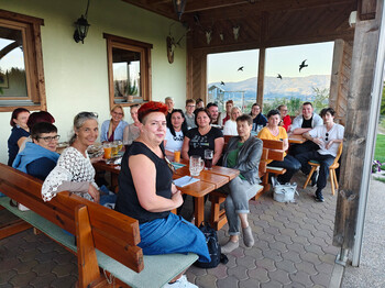 Danke für gelebte Wertschätzung – gemeinsame Jause mit dem PMS-Team in der Buschenschank Geißelbacher. Mitarbeitende der PMS Group und Pflegekräfte vom Haus Elisabeth sitzen bei Getränken auf einer Terrasse mit Blick ins Tal.