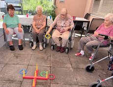 Bewohner*innen werfen bunte Ringe auf ein Zielgestell und trainieren Koordination und Aufmerksamkeit.
