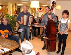 Eine Bewohnerin ist von hinten zu sehen, wie sie an ihrem Geburtstag den Musikanten zuhört. Die Musikanten stehen vor ihr und singen ein Lied zu ihren Ehren.