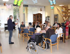 Dr. med. univ. Erwin Horst Pilgram hält im Pflegewohnhaus einen Impulsvortrag vor den anwesenden Angehörigen. Er steht im Vordergrund, spricht engagiert und vermittelt seine Inhalte mit fachlicher Kompetenz. Die Angehörigen hören aufmerksam zu.