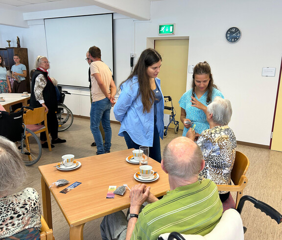 Junge Frauen im Gespräch mit Senior*innen bei Kaffee im Pflegewohnhaus Haus Franziskus