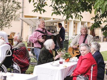 Musiker spielen für Bewohner*innen und Gäste beim Herbstfest im Garten des Caritas St. Hemma-Hauses.