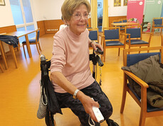 Bewohnerin sitzt im Gemeinschaftsraum mit Wii-Controller während einer Bowlingrunde in Haus Anna.