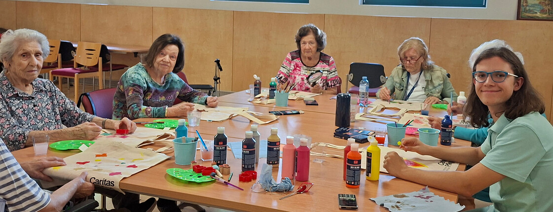 Bewohner*innen und Mitarbeitende gestalten Stofftaschen mit Farben beim kreativen Workshop im Haus Magdalena.