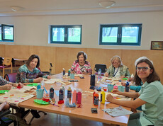 Bewohner*innen und Mitarbeitende gestalten Stofftaschen mit Farben beim kreativen Workshop im Haus Magdalena.