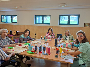 Bewohner*innen und Mitarbeitende gestalten Stofftaschen mit Farben beim kreativen Workshop im Haus Magdalena.