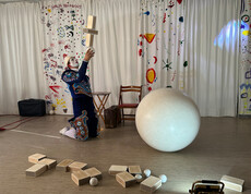 Weißclown balanciert Holzklötze und Ball auf der Bühne bei einer Zirkusvorführung in Haus Franziskus.