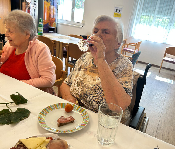 Bewohnerin genießt ein Glas Wein bei der Weinverkostung im Haus Franziskus.