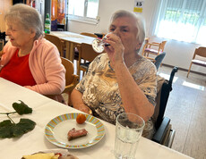 Bewohnerin genießt ein Glas Wein bei der Weinverkostung im Haus Franziskus.