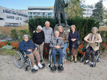 Sieben ältere Personen und eine Begleitperson versammeln sich bei einem Ausflug für ein gemeinsames Gruppenbild im Freien.