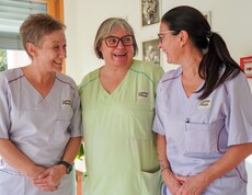 Drei Pflegerinnen stehen neben einander und lachen.