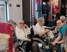 Senior*innen mit Betreuer*innen sitzen in einem Zug, teils im Rollstuhl, teils auf Sitzen