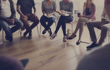 Eine Gruppe Menschen sitzt im Kreis bei einem Treffen