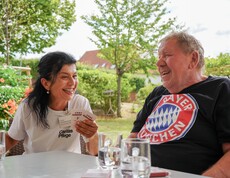 Ein Mann und eine Pflegerin spielen ein Spiel und lachen herzhaft.