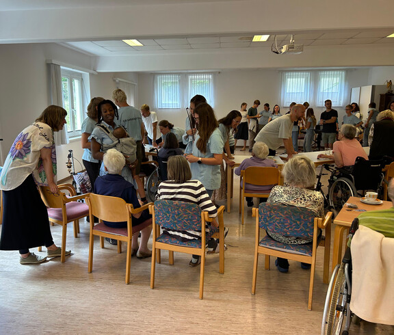 Schüler*innen unterhalten sich in Gruppen mit Senior*innen bei einer Begegnungsveranstaltung im Haus Franziskus.