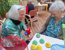 Zwei Bewohnerinnen eines Pflegewohnhauses sitzen an einem Tisch und beschäftigen sich im Rahmen einer Aktion zum Tag der Demenz mit bunten Spiel- und Bewegungsmaterialien.