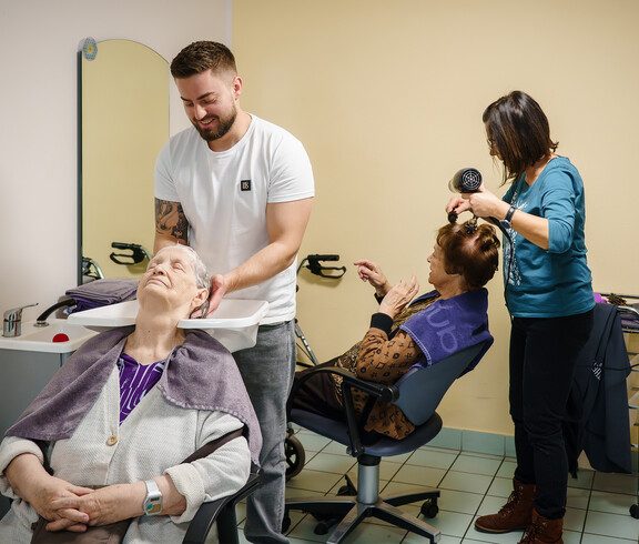 Zwei Seniorinnen erhalten Haarwäsche und Styling durch Friseurteam