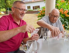 Zwei Männer spielen im Freien Karten.