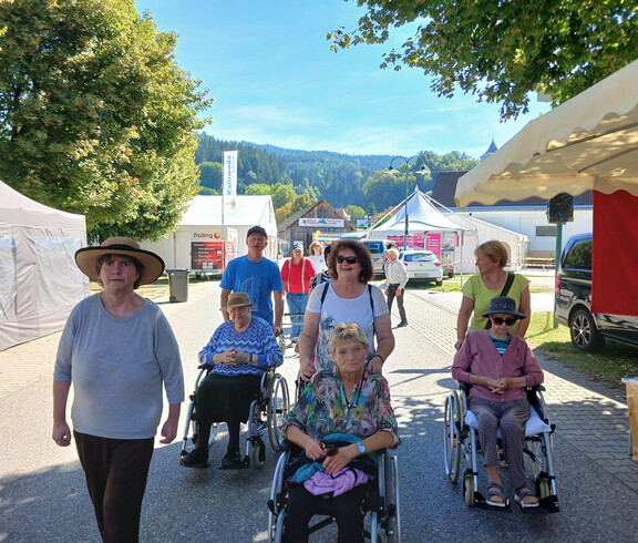 Gruppe von Bewohner*innen und Begleitpersonen bewegt sich über das Gelände des Wiesenmarkts.