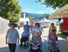 Gruppe von Bewohner*innen und Begleitpersonen bewegt sich über das Gelände des Wiesenmarkts.