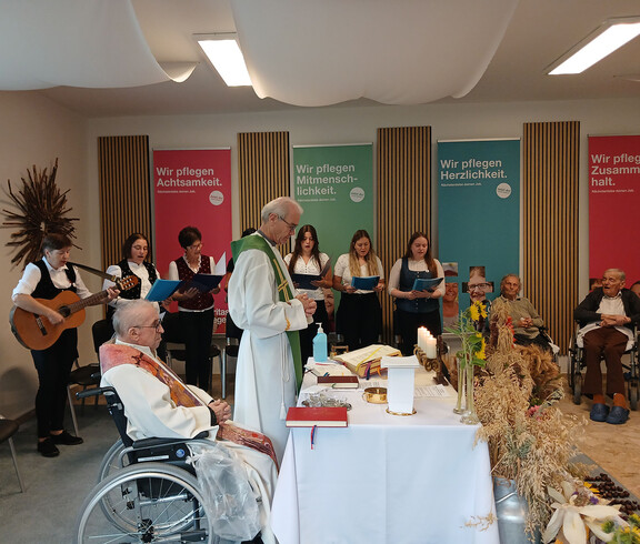 Zahlreiche Bewohner*innen und weitere Personen versammeln sich im Mehrzwecksaal zum Erntedank-Gottesdienst.