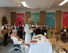 Zahlreiche Bewohner*innen und weitere Personen versammeln sich im Mehrzwecksaal zum Erntedank-Gottesdienst.