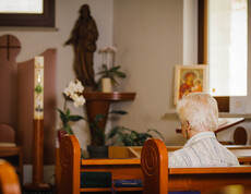 Eine Dame sitzt auf einer Kirchenbank mit dem Rücken zugekehrt und betet in der hauseigenen Kapelle.