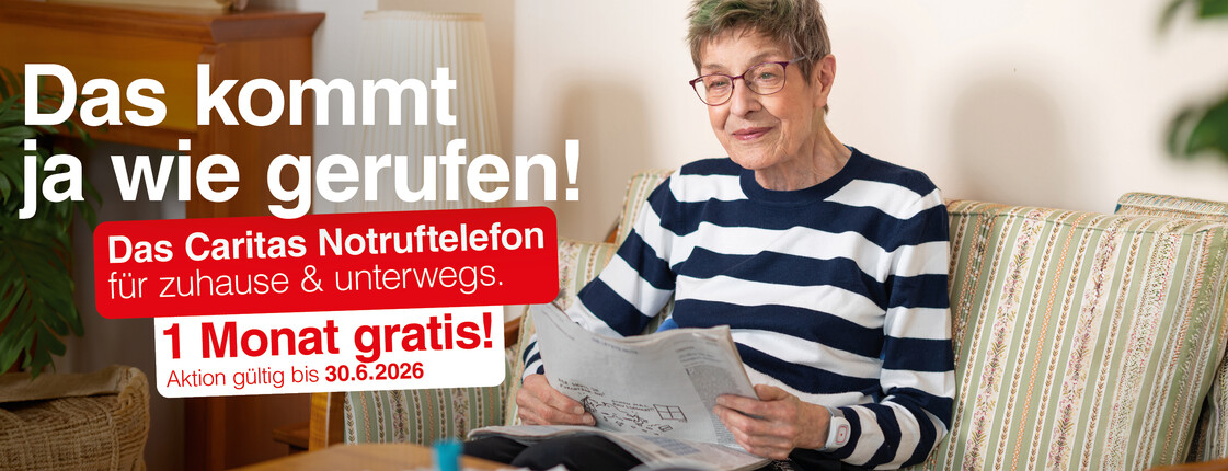 Ältere Person sitzt auf einem Sofa im Wohnzimmer und liest eine Zeitung. Links im Bild Werbetext: „Das kommt ja wie gerufen! Das Caritas Notruftelefon für zuhause & unterwegs. 1 Monat gratis! Aktion gültig bis 30.6.2026“.