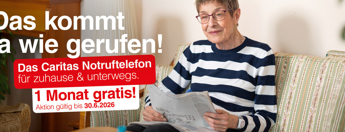 Ältere Person sitzt auf einem Sofa im Wohnzimmer und liest eine Zeitung. Links im Bild Werbetext: „Das kommt ja wie gerufen! Das Caritas Notruftelefon für zuhause & unterwegs. 1 Monat gratis! Aktion gültig bis 30.6.2026“.