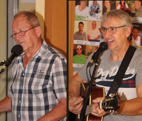 Zwei Männer singen gemeinsam am Mikrofon – einer spielt Gitarre, der andere begleitet am Keyboard. Im Hintergrund ist die Vorstellwand des Pflegepersonals aus dem Pflegewohnhaus zu sehen.