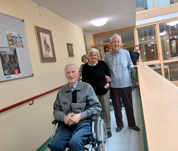 Vier ältere Personen machen sich nach dem gemeinsamen Besuch auf den Weg durch den Gang des Pflegewohnhauses.