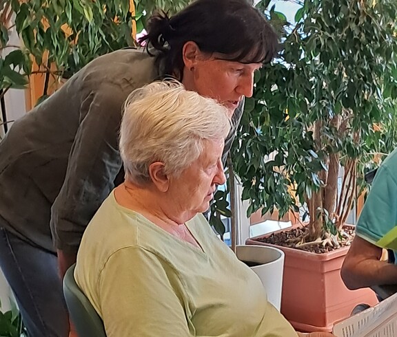 Eine Bewohnerin des Pflegewohnhauses nimmt im Rahmen des Tags der Demenz an einem gemeinsamen Singangebot teil, begleitet von einer Mitarbeiterin.